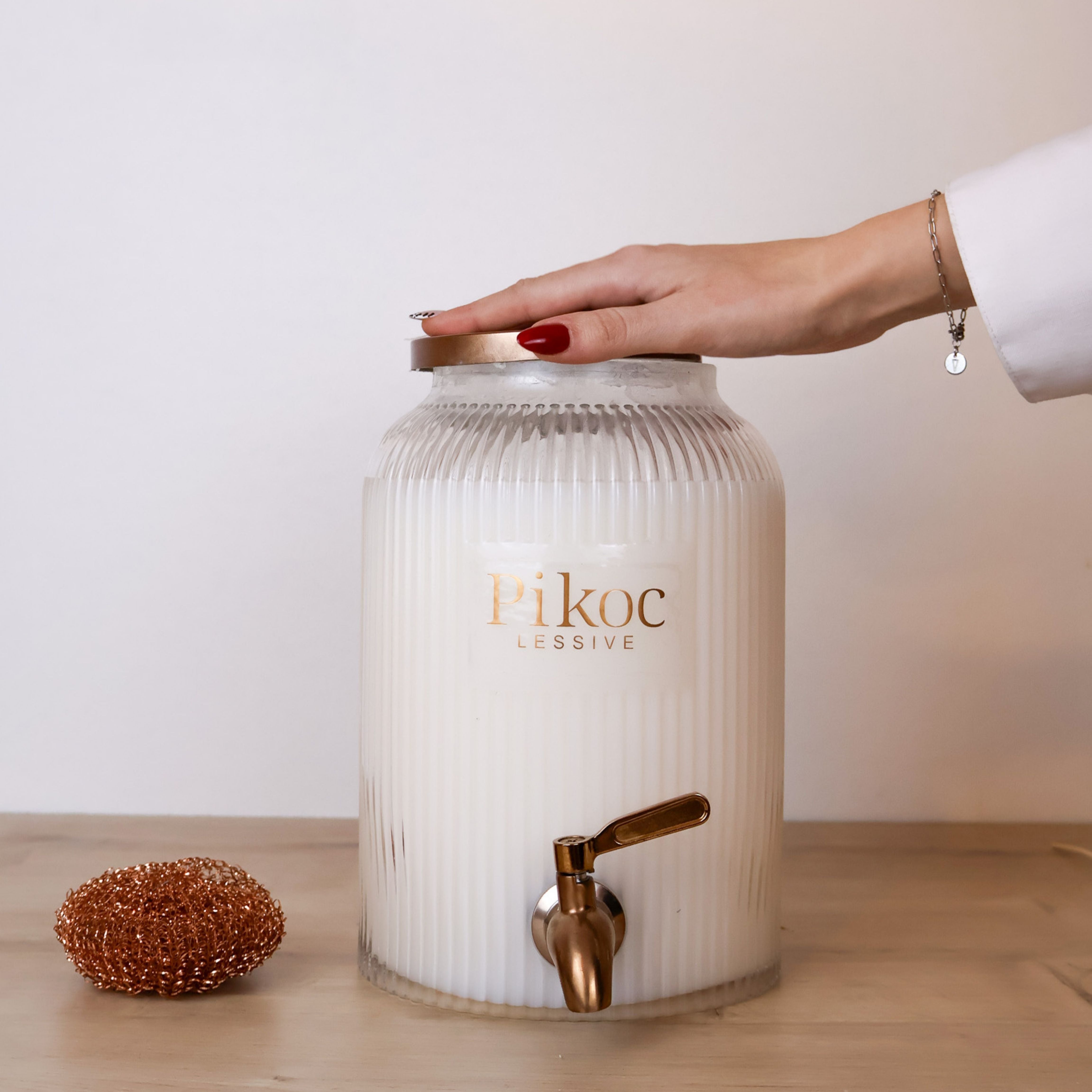 Fontaine à lessive 4L Pikoc Bois Mythique, posé sur un meuble en bois avec le couvercle en main