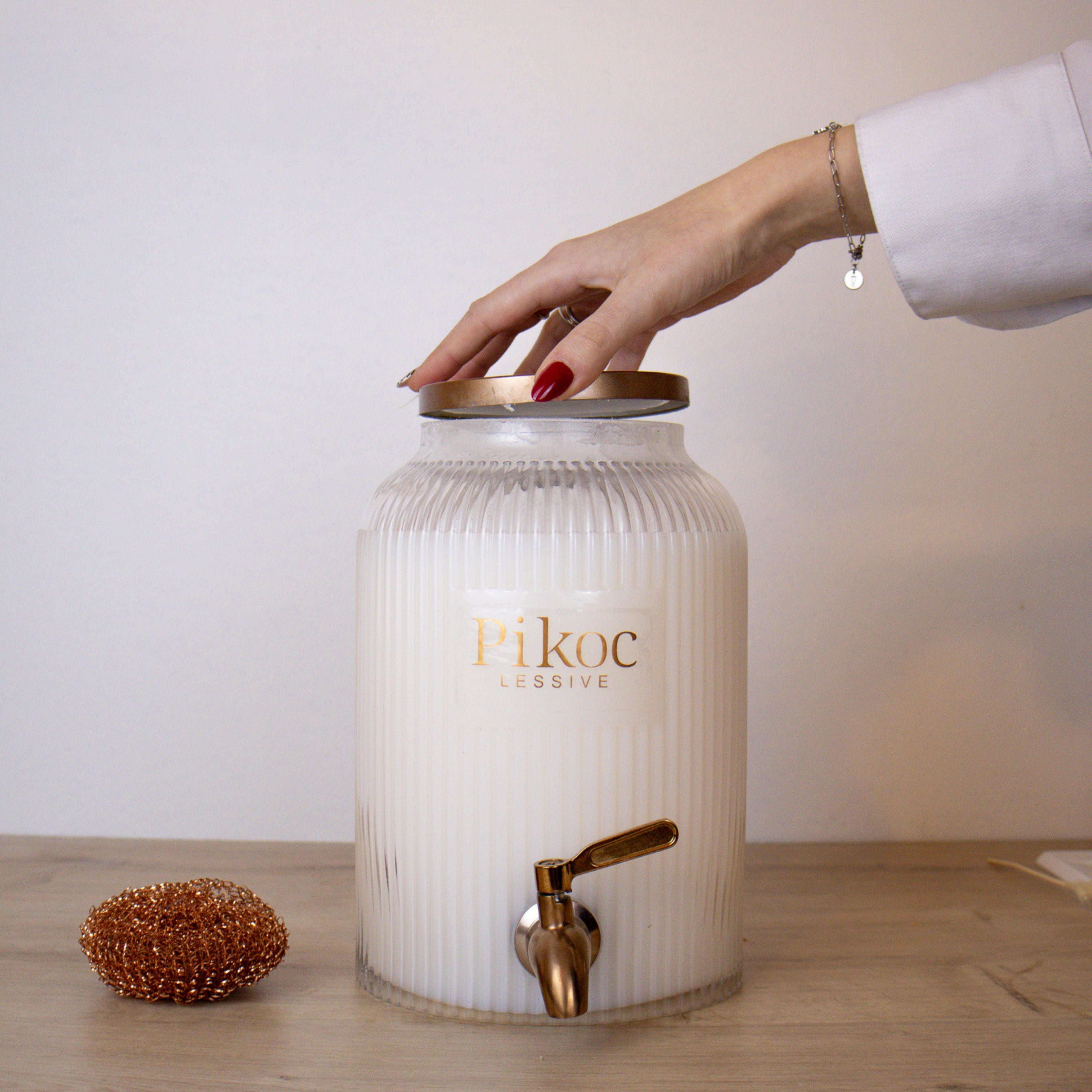 Fontaine à lessive 4L Pikoc Éclat d’Iris, posé sur un meuble en bois avec le couvercle en main