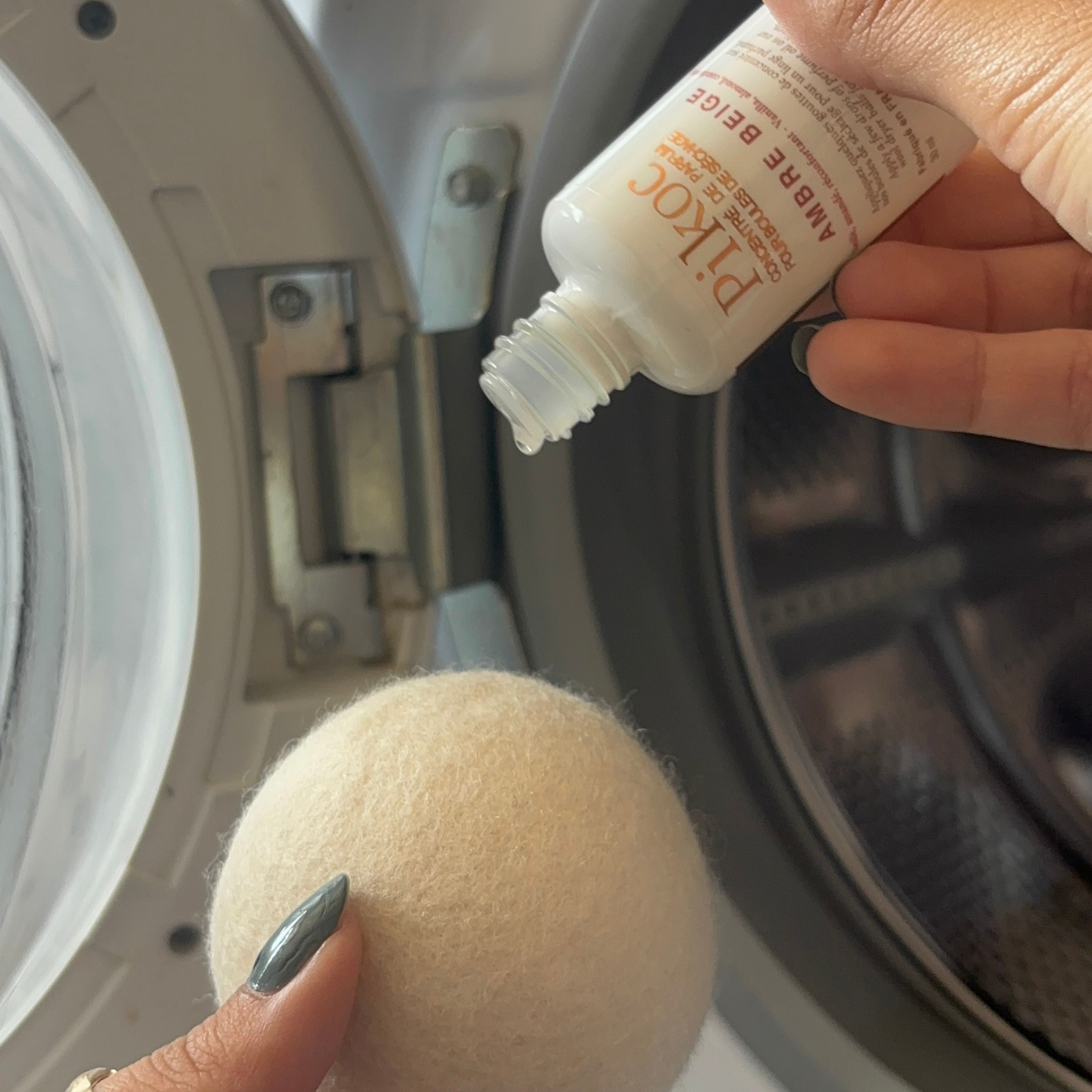 Set de séchage Pikoc Ambre Beige, le concentré de parfum en utilisation sur la boule de séchage devant le sèche linge