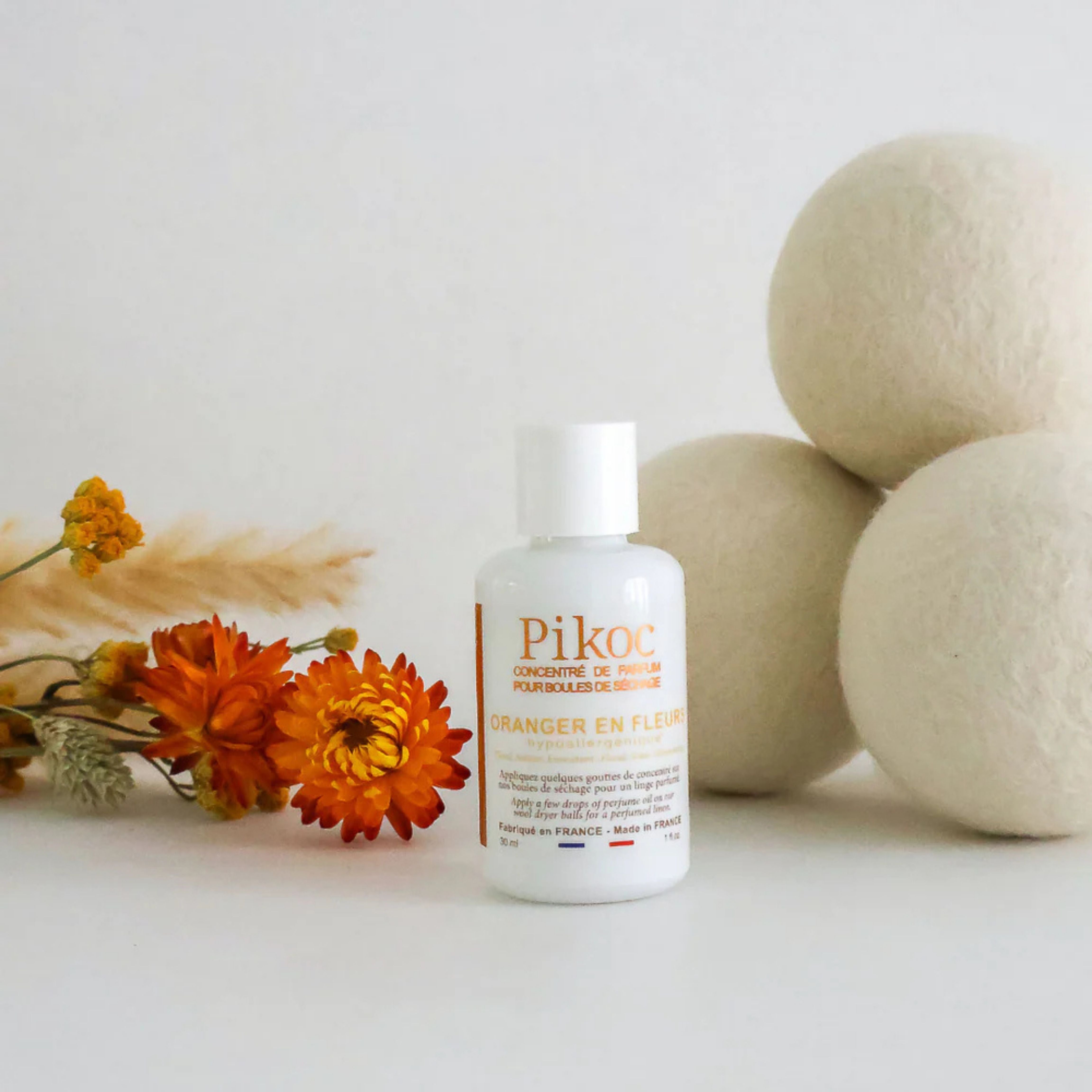 Set de séchage Pikoc Oranger en Fleurs, le concentré de parfum et les boules de séchage posé avec une fleur orange
