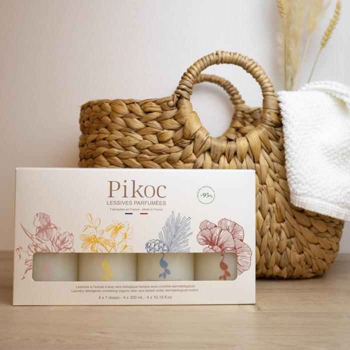 Coffret découverte Pikoc lessives 300mL, posé devant un panier en osier, ambiance bohème chic