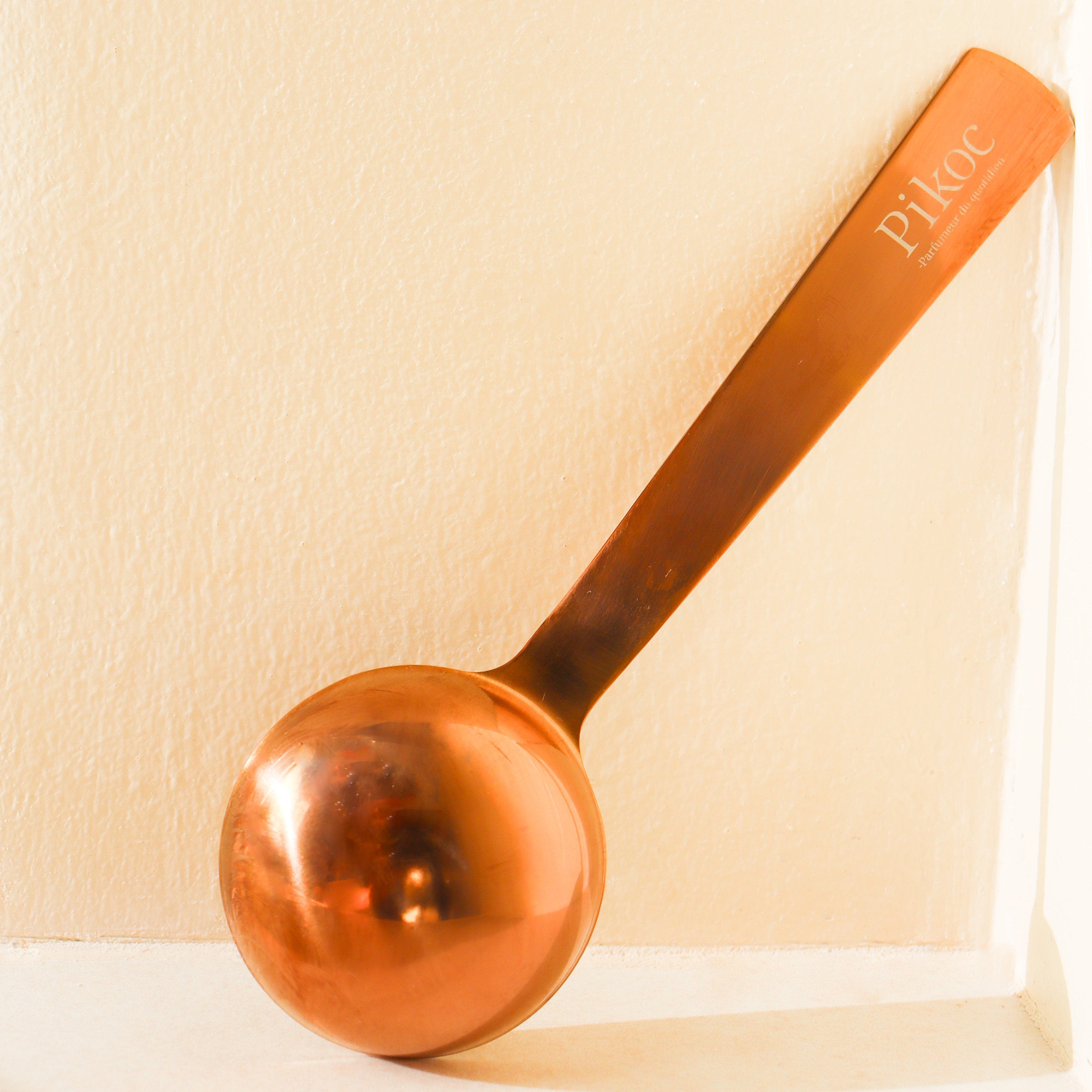 Cuillère doseuse Pikoc de dos contre un mur