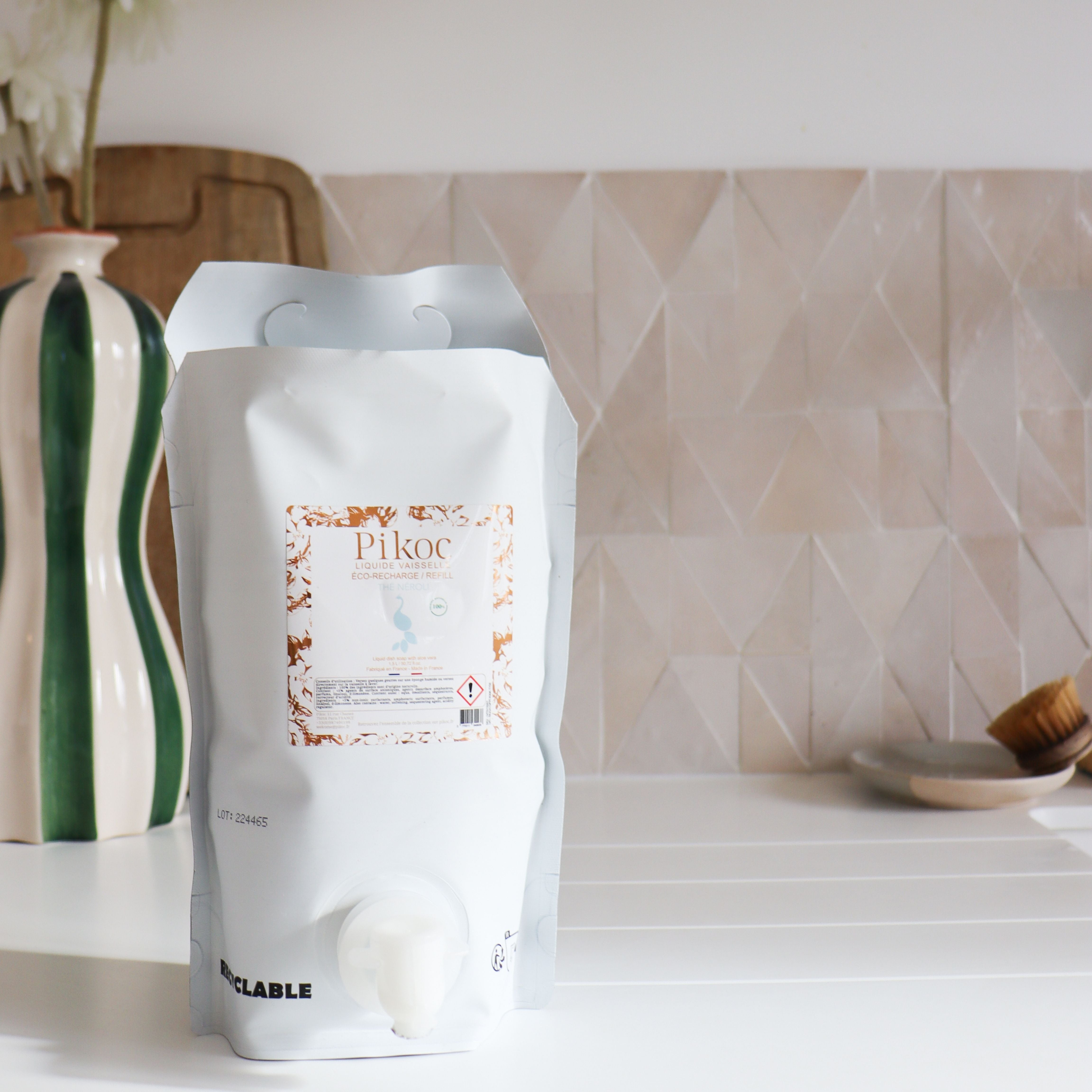 Éco-recharge Liquide vaisselle Pikoc Thé Néroli, 1,5L, posé à côté d’un évier