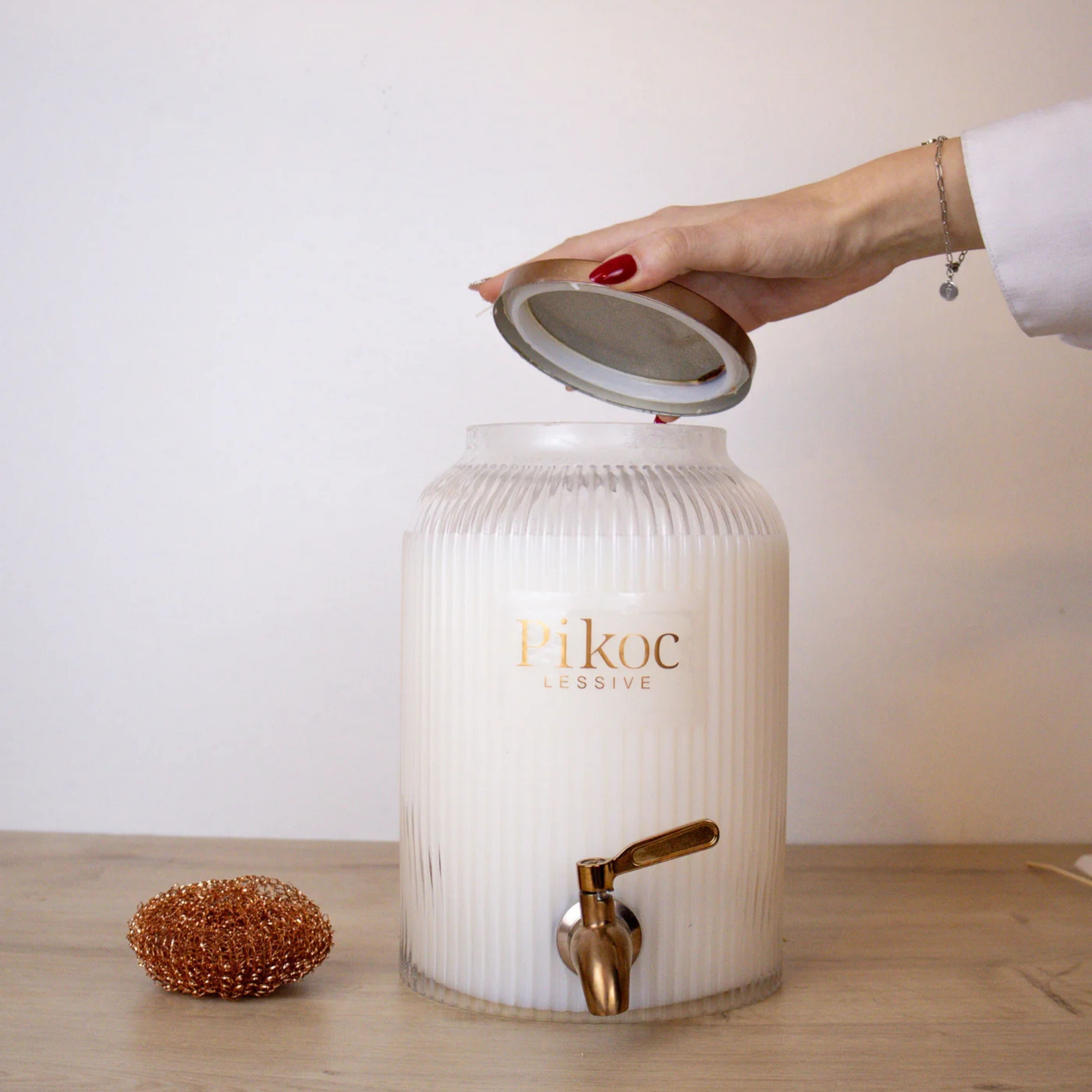 Fontaine à lessive 4L Pikoc Oranger en Fleurs, posé sur un meuble en bois avec le couvercle en main