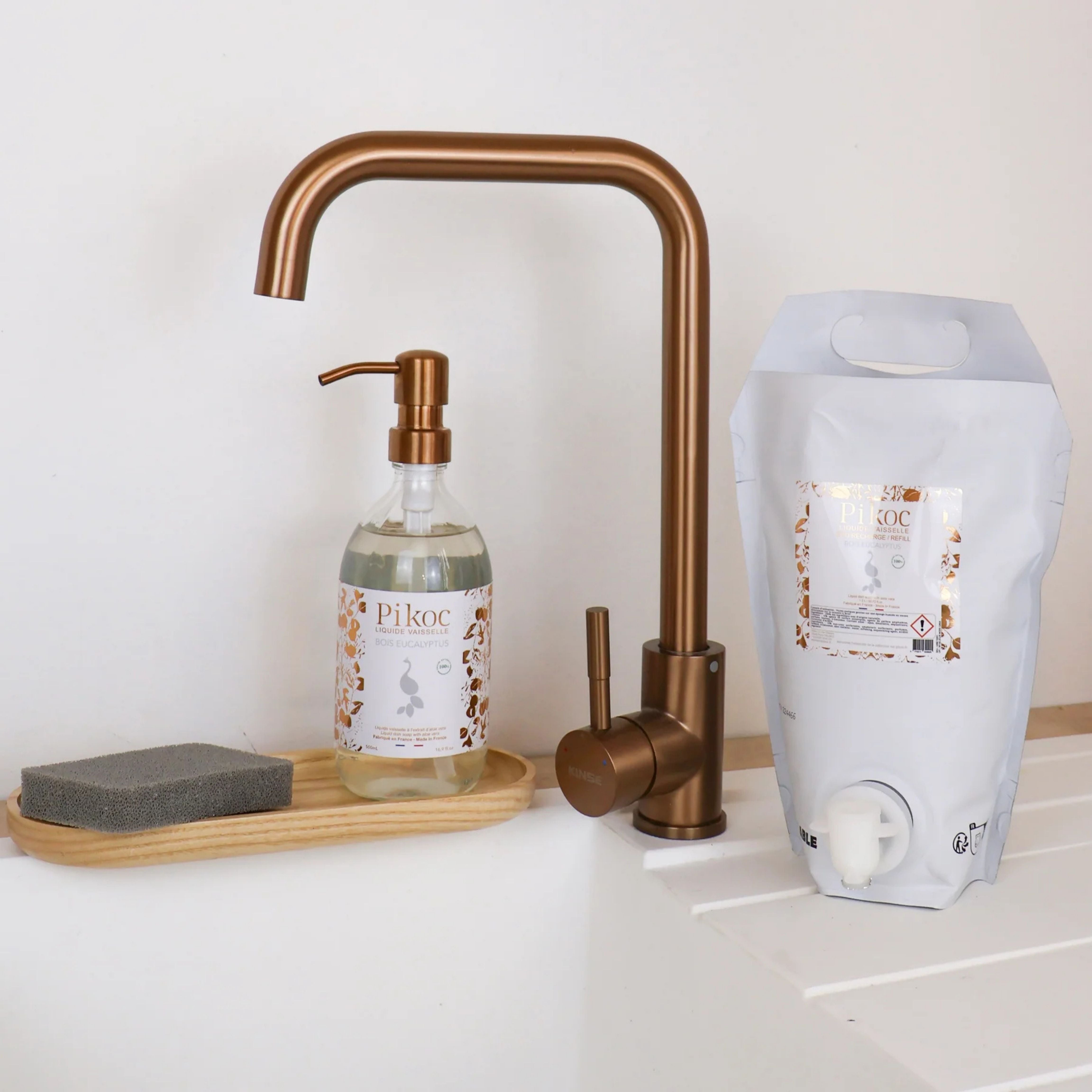 Liquide vaisselle et Eco recharge Pikoc Bois Eucalyptus, 490mL et 1,5L, posé à côté d’un évier