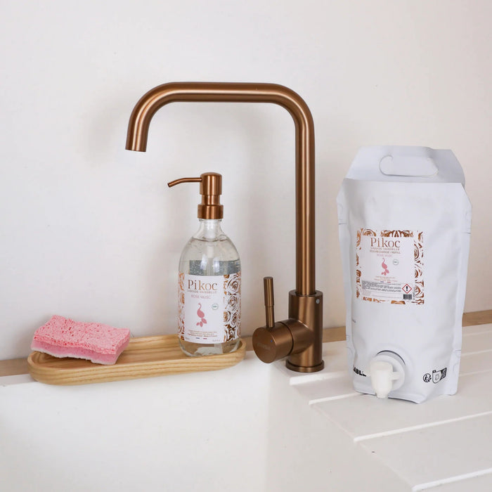 Liquide vaisselle et Eco recharge Pikoc Rose Musc, 490mL et 1,5L, posé à côté d’un évier