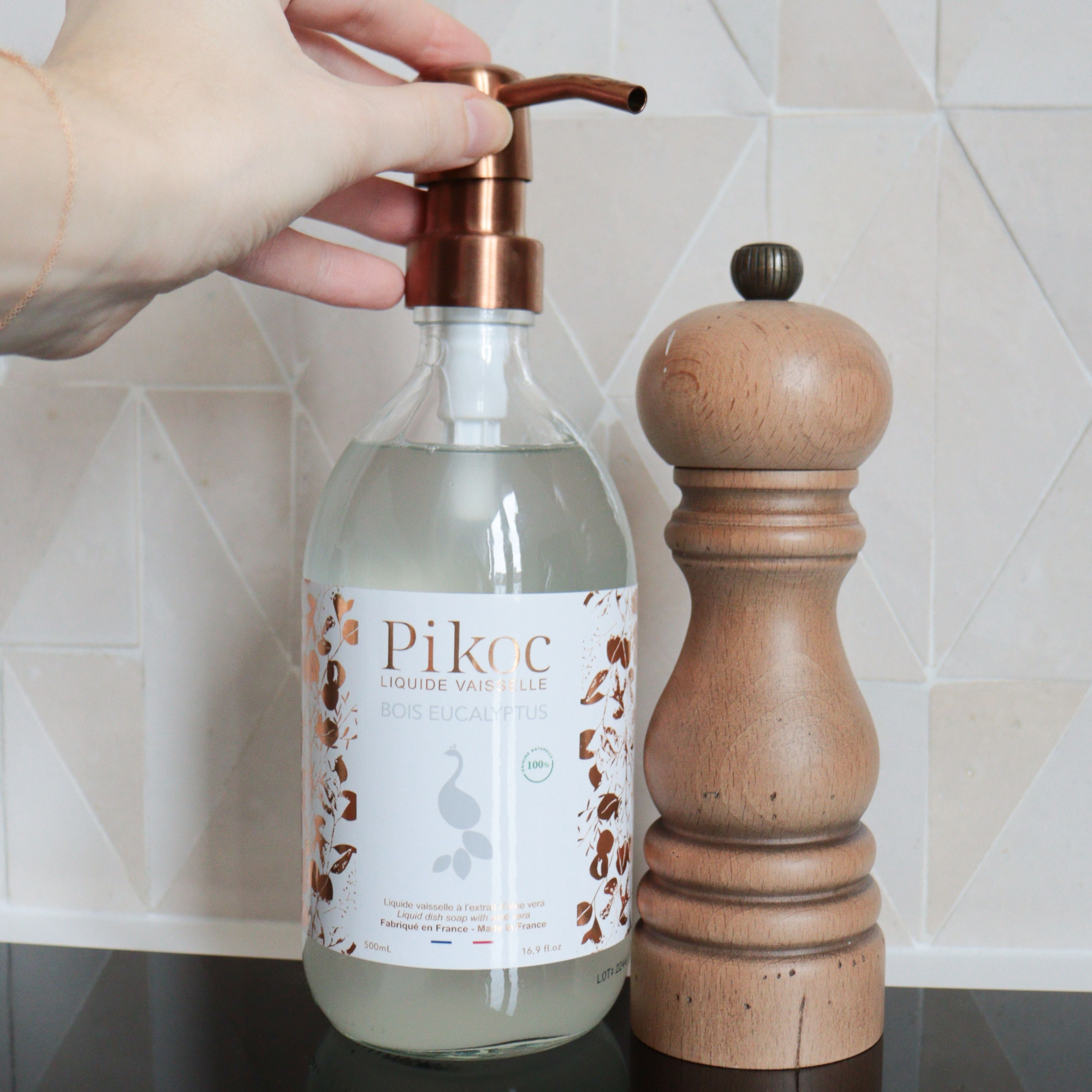 Liquide vaisselle Pikoc Bois Eucalyptus, 490mL, posé sur un meuble de cuisine avec un moulin à poivre