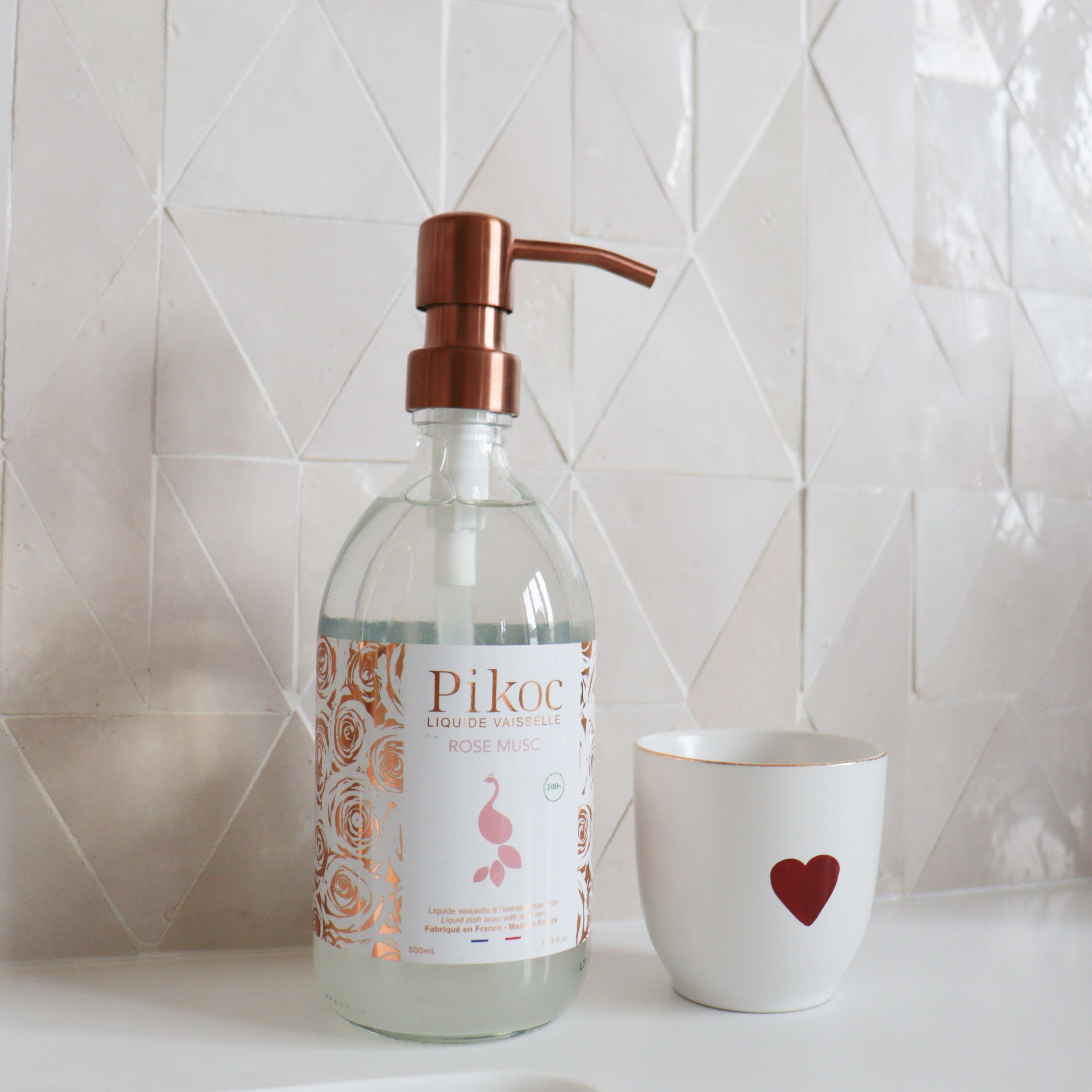 Liquide vaisselle Pikoc Rose Musc, 490mL, posé à côté d’un évier et d’une tasse avec un coeur