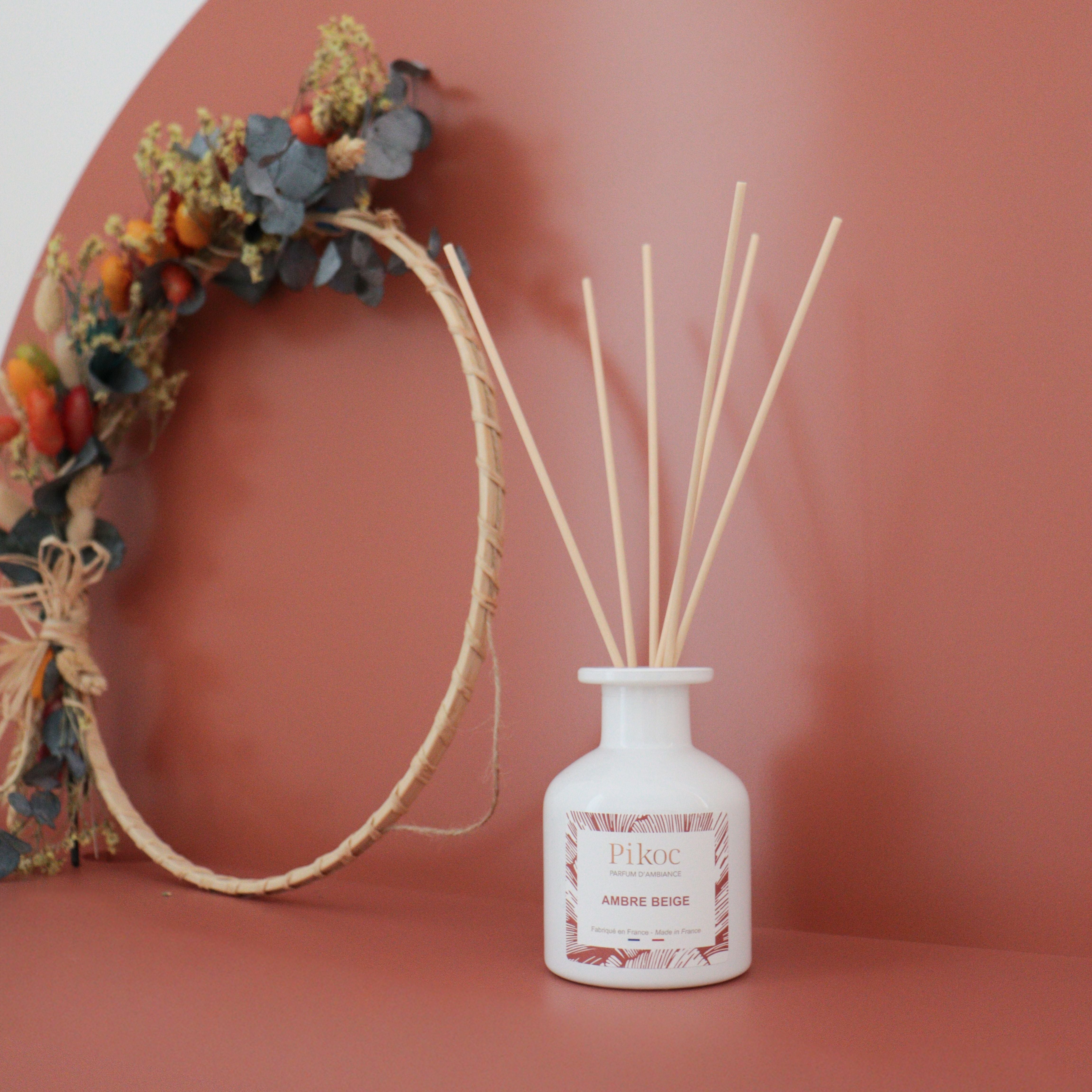 Parfum d’ambiance Pikoc Ambre Beige, 150mL, posé à côté une couronne de plantes en osier