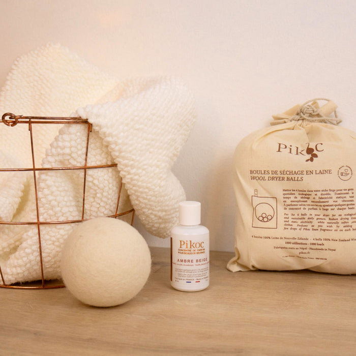 Set de séchage Pikoc Ambre Beige, posé sur un meuble en bois avec un panier de linge, concentré de parfum et boules de séchage