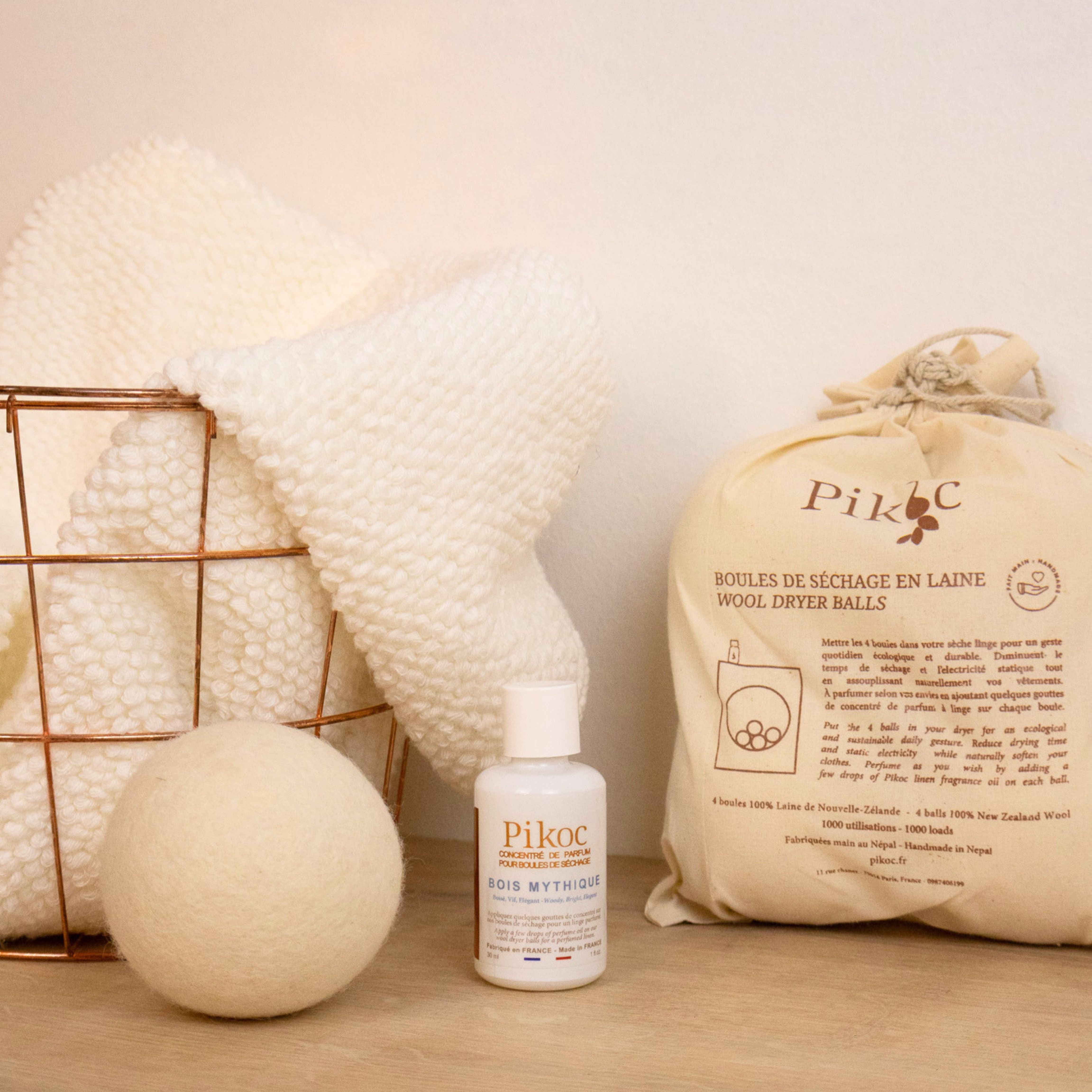 Set de séchage Pikoc Bois Mythique, posé sur un meuble en bois avec un panier de linge, concentré de parfum et boules de séchage