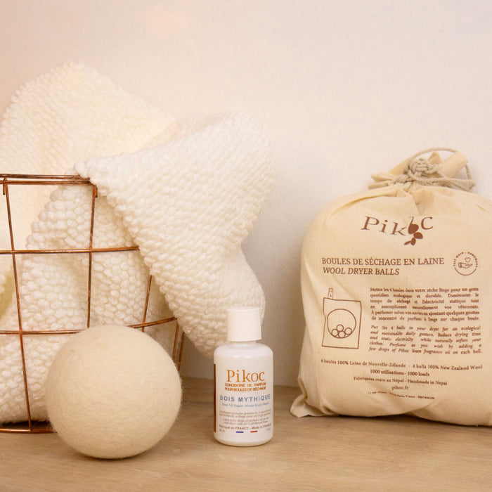 Set de séchage Pikoc Bois Mythique, posé sur un meuble en bois avec un panier de linge, concentré de parfum et boules de séchage