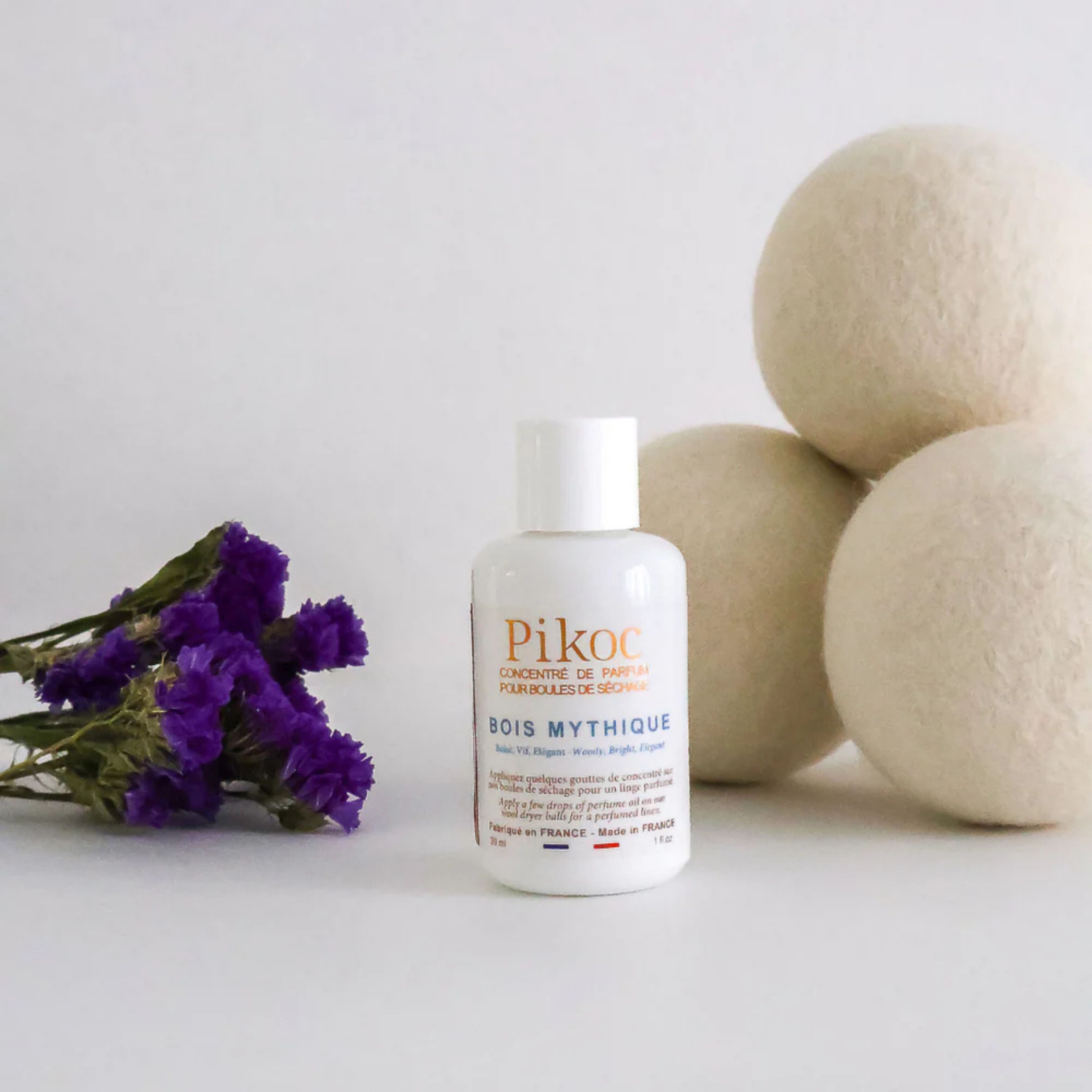 Set de séchage Pikoc Bois Mythique, le concentré de parfum et les boules de séchage posé avec une fleur violette