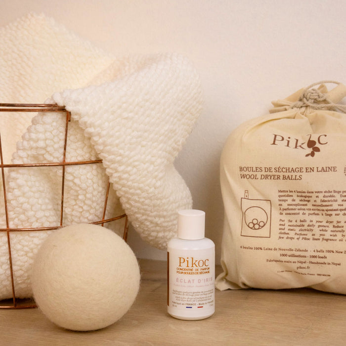 Set de séchage Pikoc Éclat d’Iris, posé sur un meuble en bois avec un panier de linge, concentré de parfum et boules de séchage