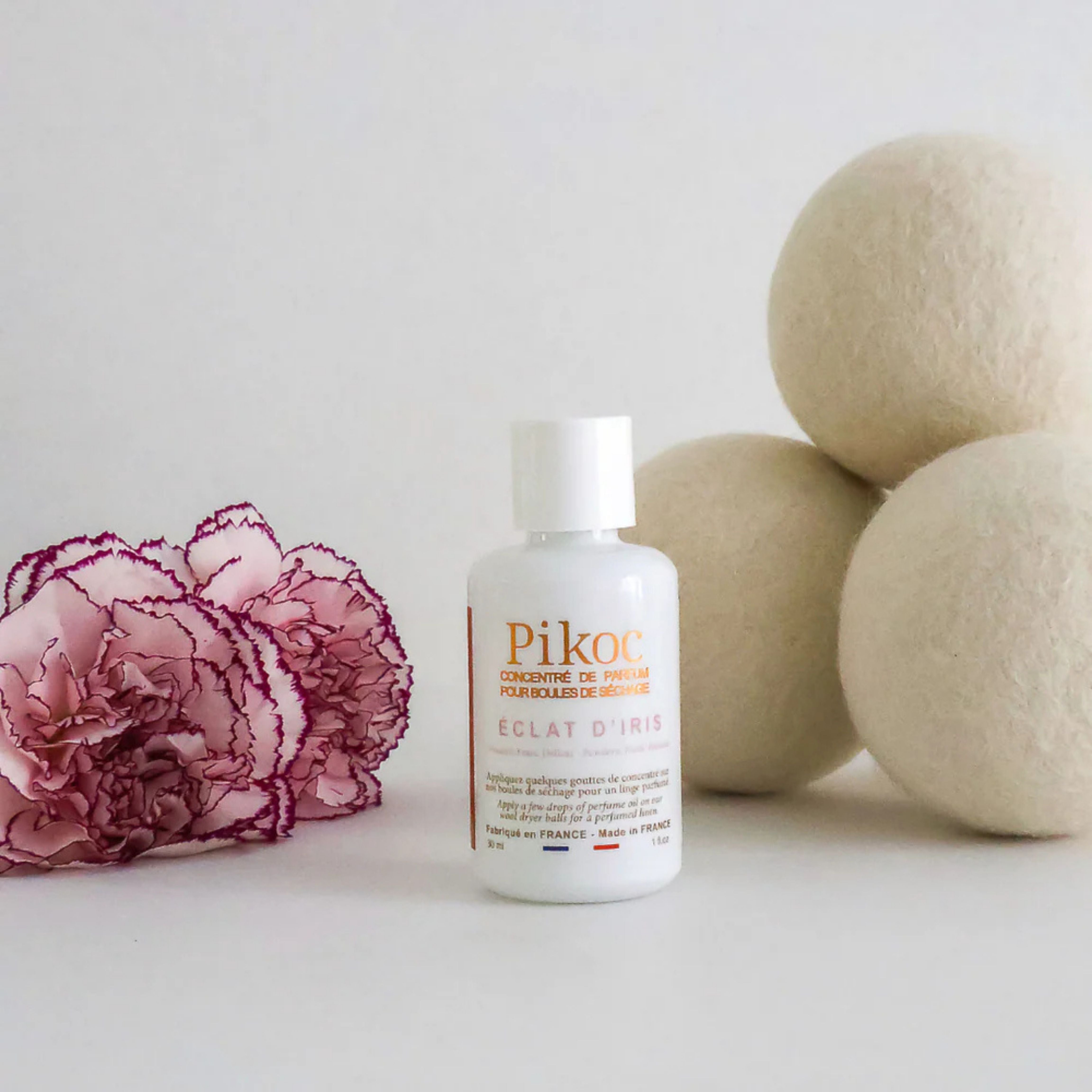 Set de séchage Pikoc Éclat d’Iris, le concentré de parfum et les boules de séchage posé avec une fleur rose et violette