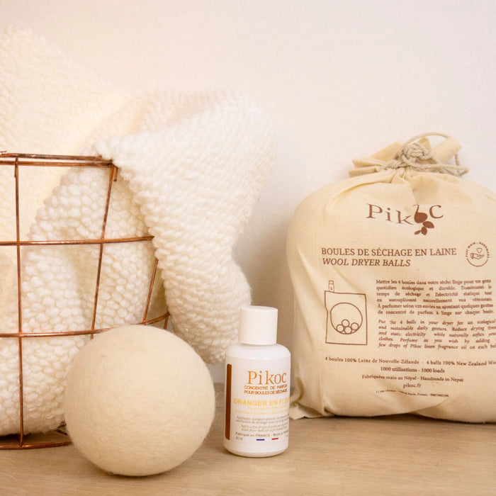 Set de séchage Pikoc Oranger en Fleurs, posé sur un meuble en bois avec un panier de linge, concentré de parfum et boules de séchage